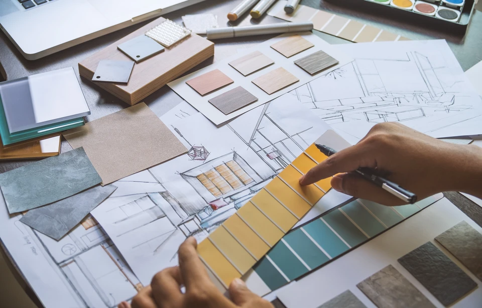 Espace de travail d'architecte d'intérieur avec mains sélectionnant des échantillons de couleurs jaunes sur nuancier