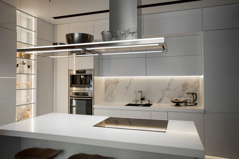Cuisine moderne haut de gamme avec îlot central blanc, plan de travail en quartz, crédence en marbre veiné