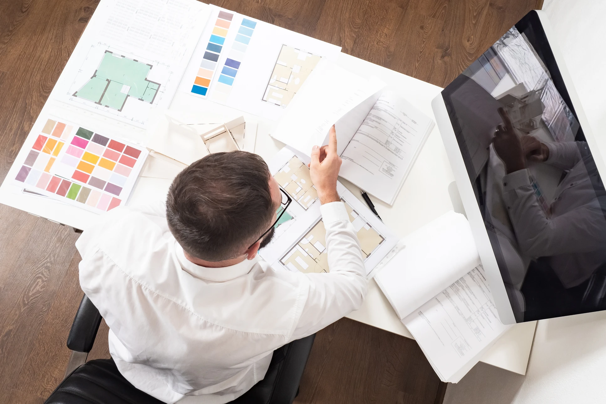 Architecte ou designer travaillant sur des plans d'aménagement intérieur, consultant des nuanciers de couleurs et échantillons de matériaux