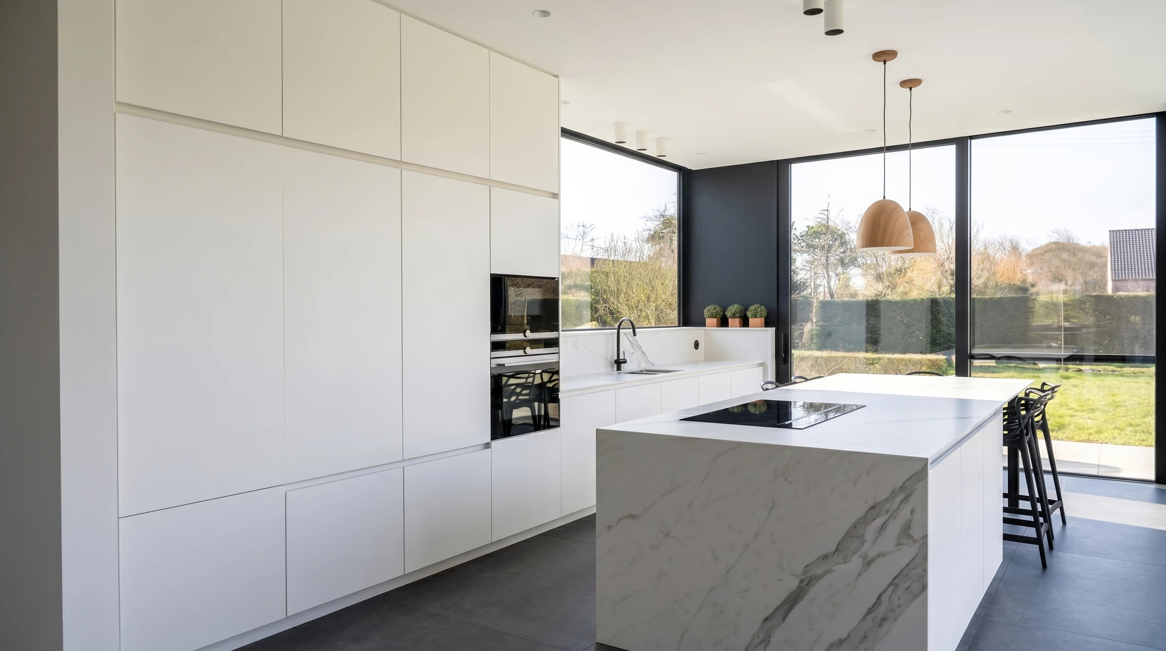 Cuisine moderne haut de gamme avec îlot central blanc, plan de travail en quartz, crédence en marbre veiné