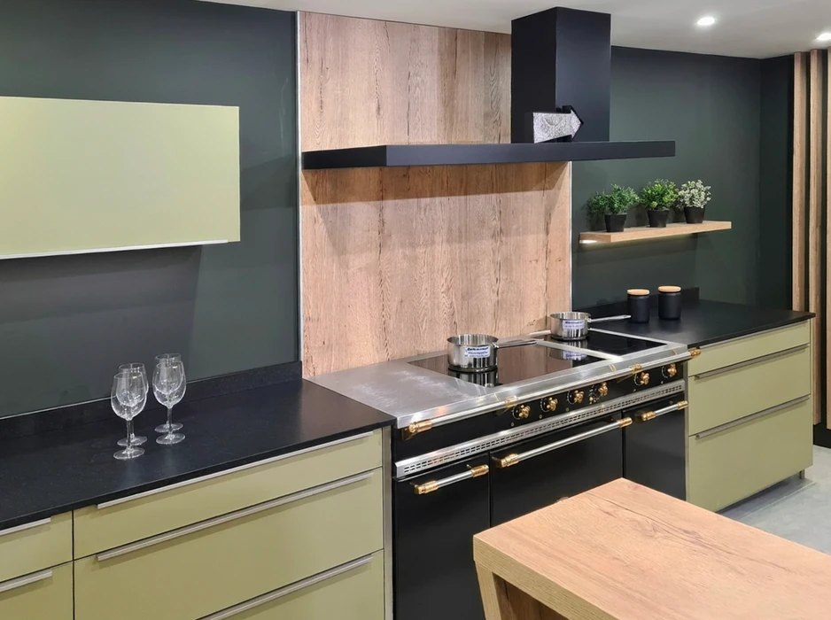 Cuisine moderne ouverte avec îlot central en bois et chaises grises, personne préparant un repas