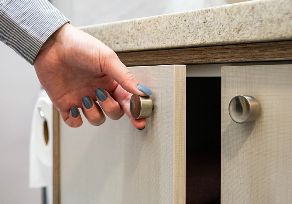 Salon moderne avec meuble TV intégré en bois foncé, étagères illuminées contenant objets décoratifs, écran plat encastré